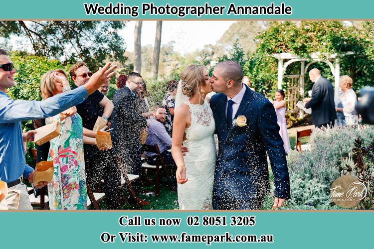 Photo of the Bride and the Groom kissing while showering rice by the visitors Annandale NSW 2038