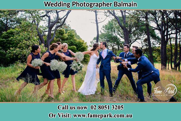 Photo of the Bride and the Groom kissing while teasing by the entourage Balmain NSW 2041