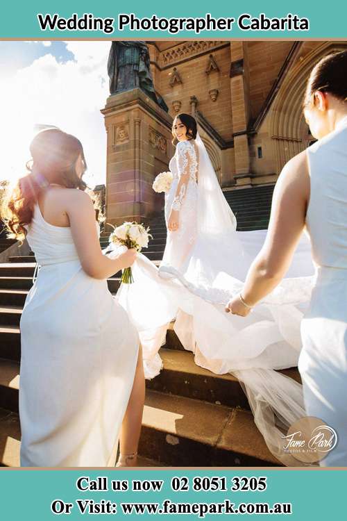 Photo of the Bride smiling on the bridesmaid holding the tail of her wedding gown at the front of the church Cabarita NSW 2137