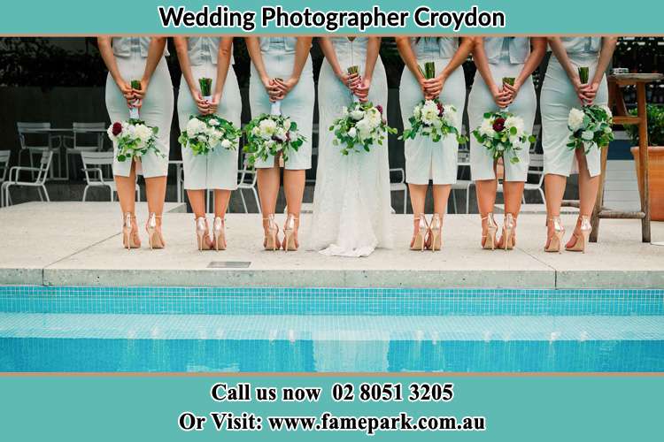 Behind photo of the Bride and the bridesmaids holding flowers near the pool Croydon NSW 2132