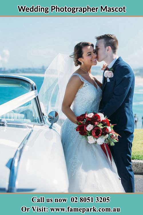 Photo of the Groom kiss the Bride besides the bridal car Mascot NSW 2020