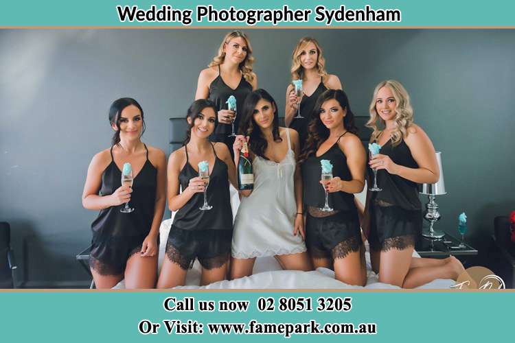 Photo of the Bride and the bridesmaids wearing lingerie and holding glass of wine on bed Sydenham NSW 2044